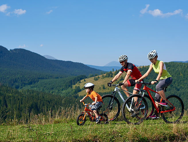 Un couple fait du vélo avec leur enfant en montagne