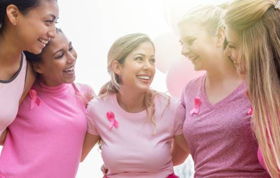 Groupe de participantes portant des vêtements roses et des rubans roses de sensibilisation lors d’un événement de soutien à la lutte contre le cancer du sein.