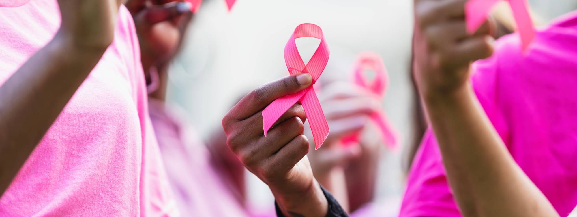 Plusieurs personnes tenant des rubans roses, symbole de la campagne de sensibilisation au cancer du sein.