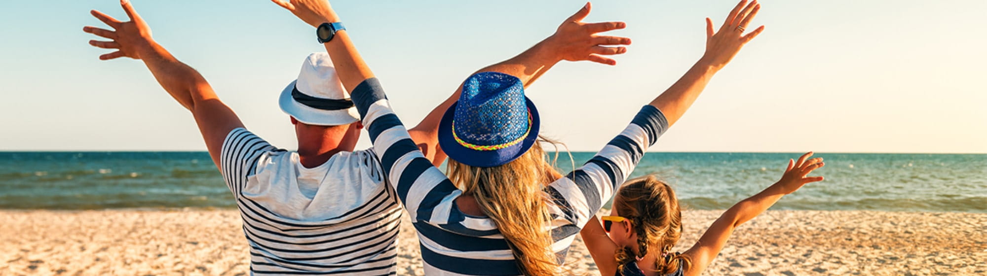 Une famille qui lèvent les bras sur la plage