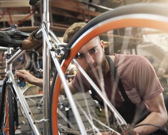 un homme qui regarde les roues d'un vélo pour les réparer