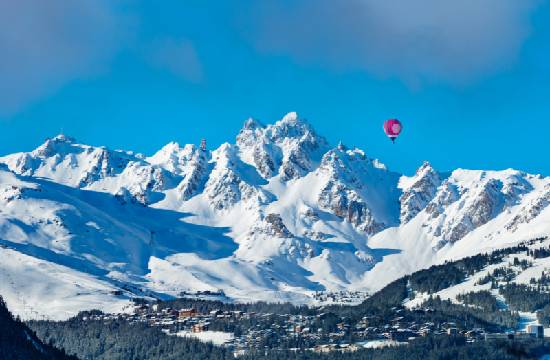 Les montagnes enneigées avec une montgolfière au dessus.