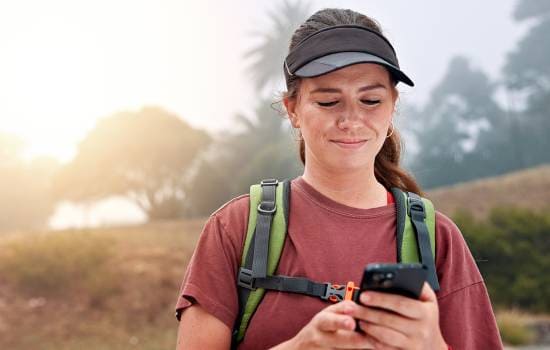 Une femme faisant de la randonnée regardant son téléphone