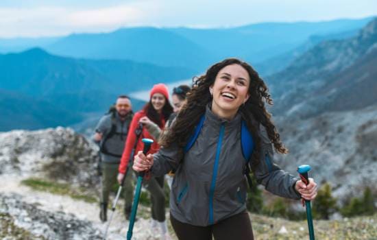 Groupe de randonneurs progressant sur un sentier de montagne avec bâtons de marche et vue sur les reliefs environnants.