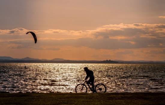 Un cycliste au bord de la mer au couché du soleil