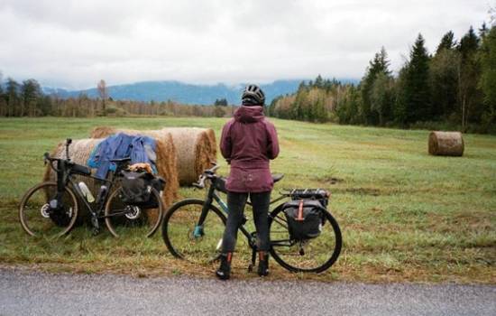 Cycliste avec un vélo dans un paysage rural entouré de bottes de foin