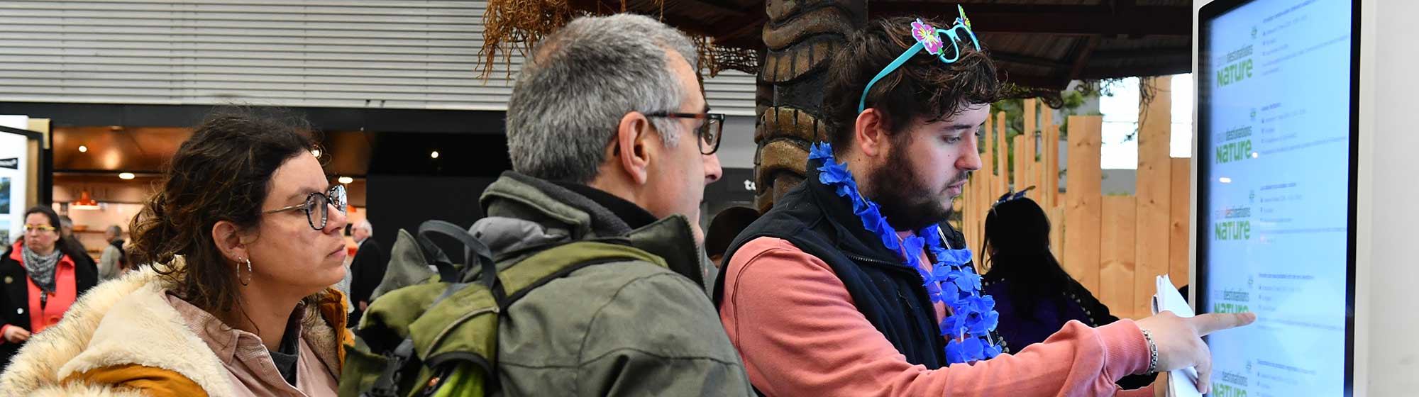 Un hôte aide des visiteurs à se guider avec une borde numérique
