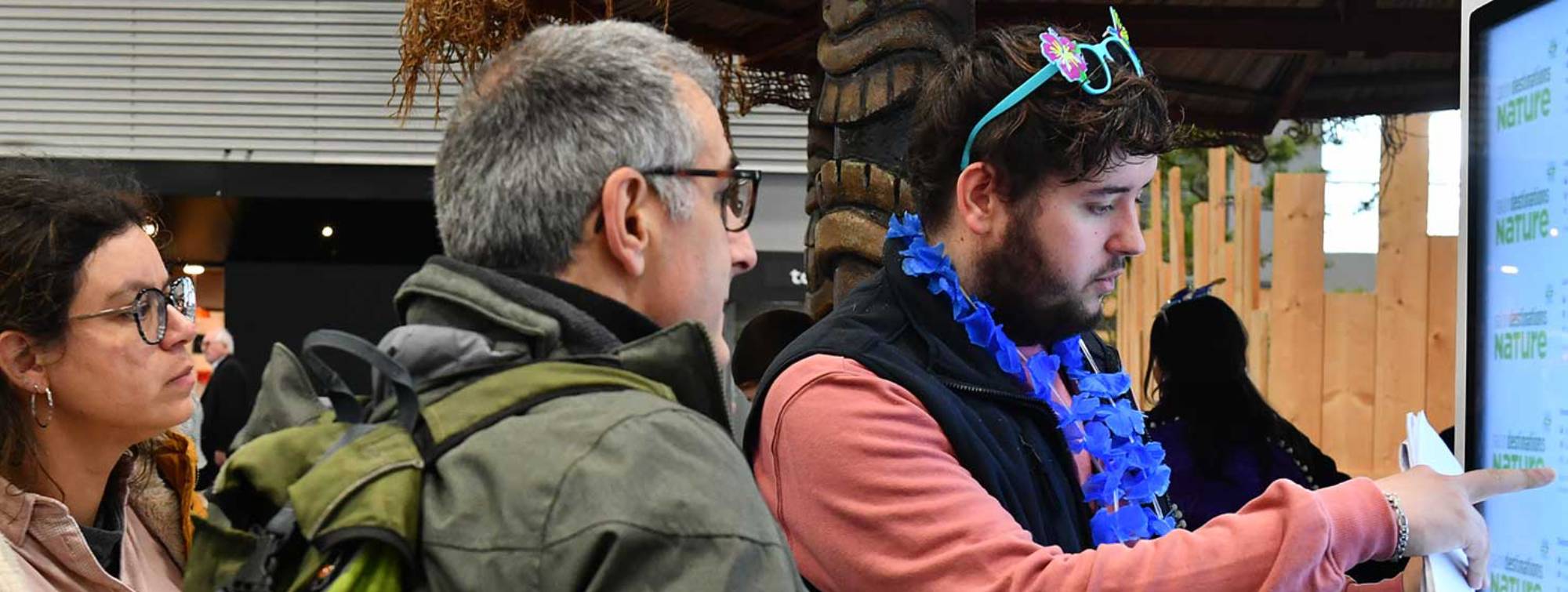 Un hôte aide des visiteurs à se guider avec une borde numérique