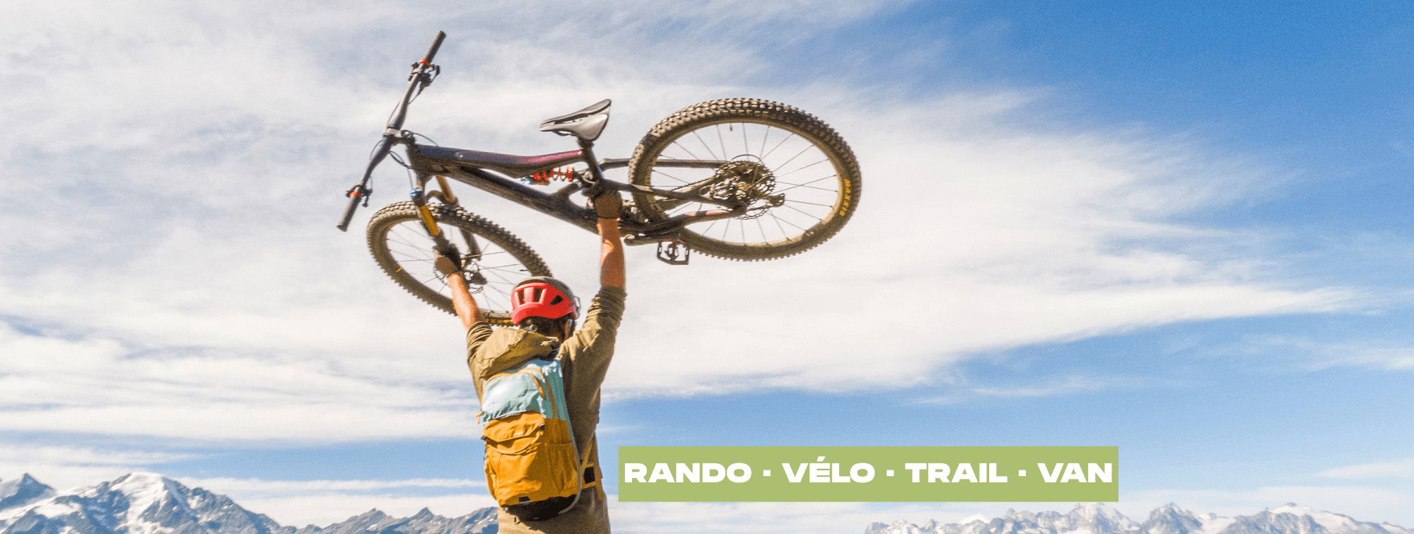 un homme qui soulève son vélo face à la montagne