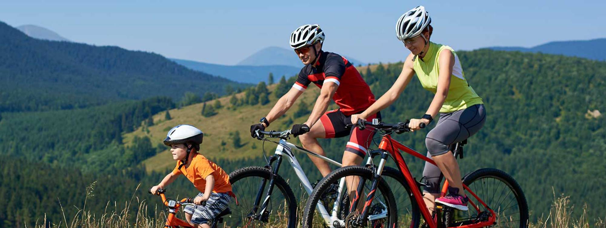 Un couple fait du vélo avec leur enfant en montagne