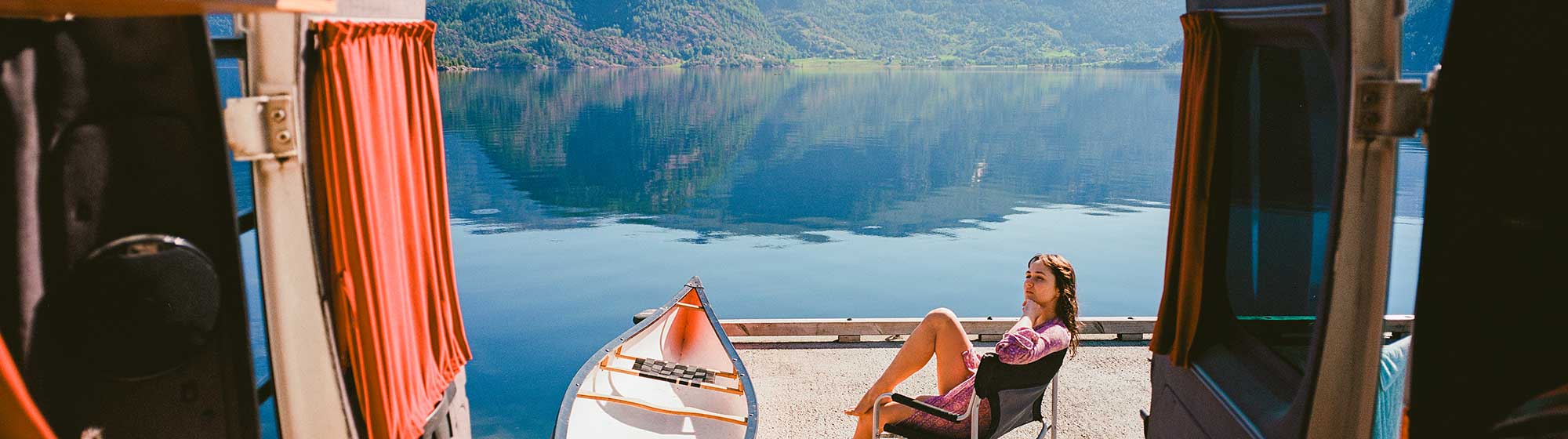 Une femme assise sur un ponton face à son van