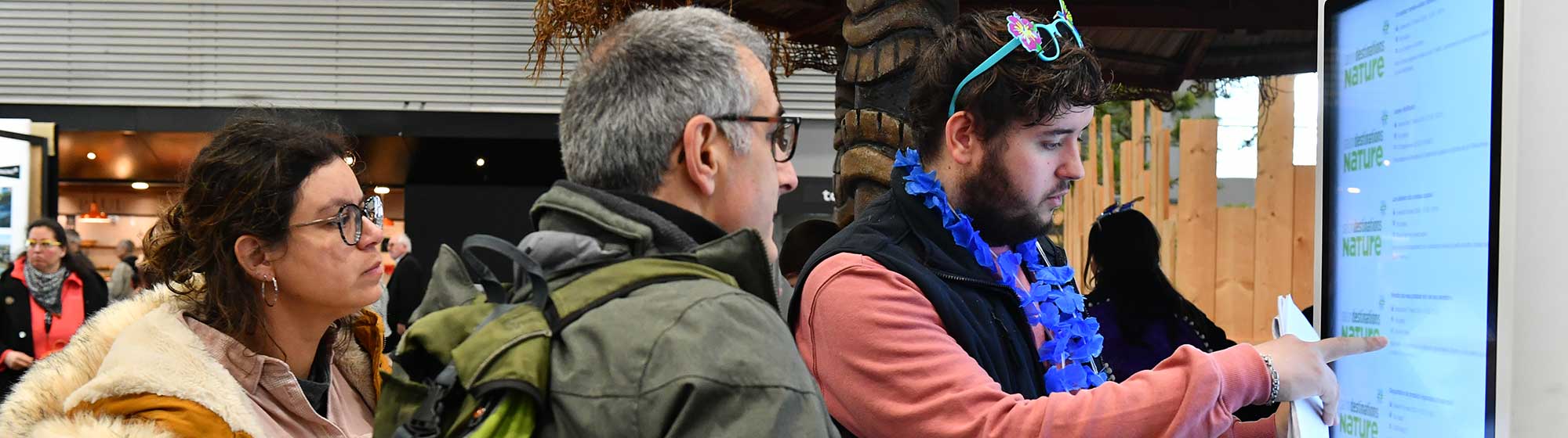 Un hôte aide des visiteurs à se guider avec une borde numérique