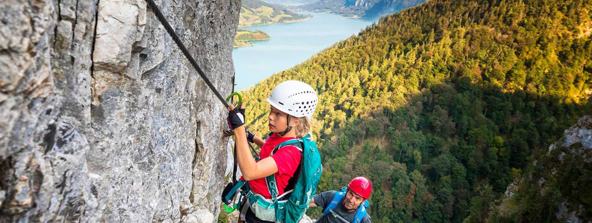 Un père fait de l'escalade en montagne avec sa fille