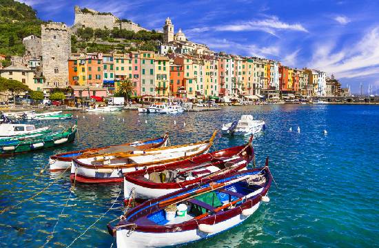 Barques colorées amarrées dans le port de Portovenere, avec en arrière-plan les maisons multicolores et le château Doria, en Ligurie, Italie.