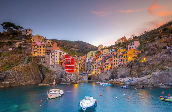 Petit port de pêche de Riomaggiore au coucher du soleil, entouré de maisons colorées et de falaises, dans les Cinque Terre, Italie.