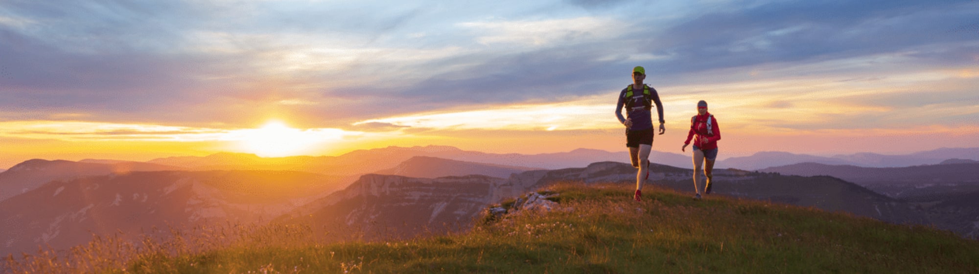 Un coureur court dans la montagne avec le soleil derrière lui