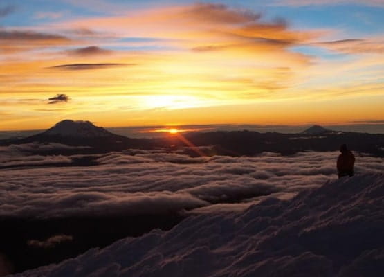 Un coucher de soleil sur des montagnes entourées de nuages
