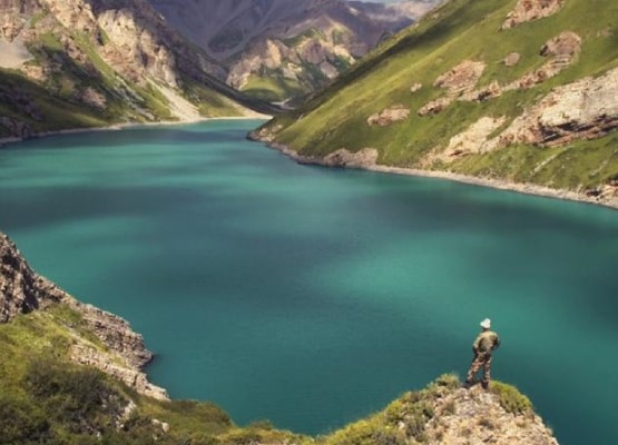 Un marcheur observe le lac au milieu de la montagne