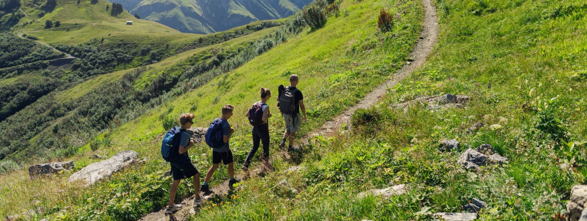 4 personnes qui font de la randonnée sur un sentier en montagne