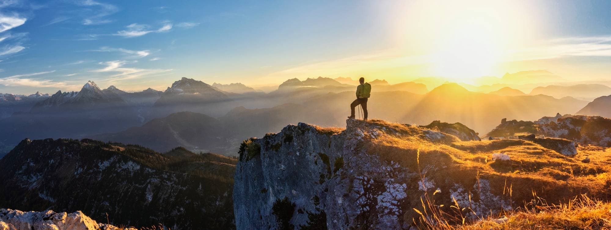 un homme en haut d'une montagne au lever du soleil