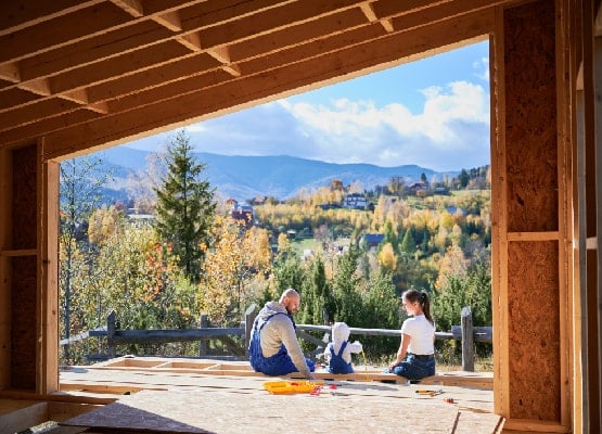 Un couple avec son enfant assis sur une terrasse en face des montagnes .