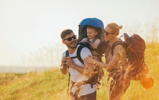 Un couple avec un enfant sur le dos en train de se balader dans un champs. 