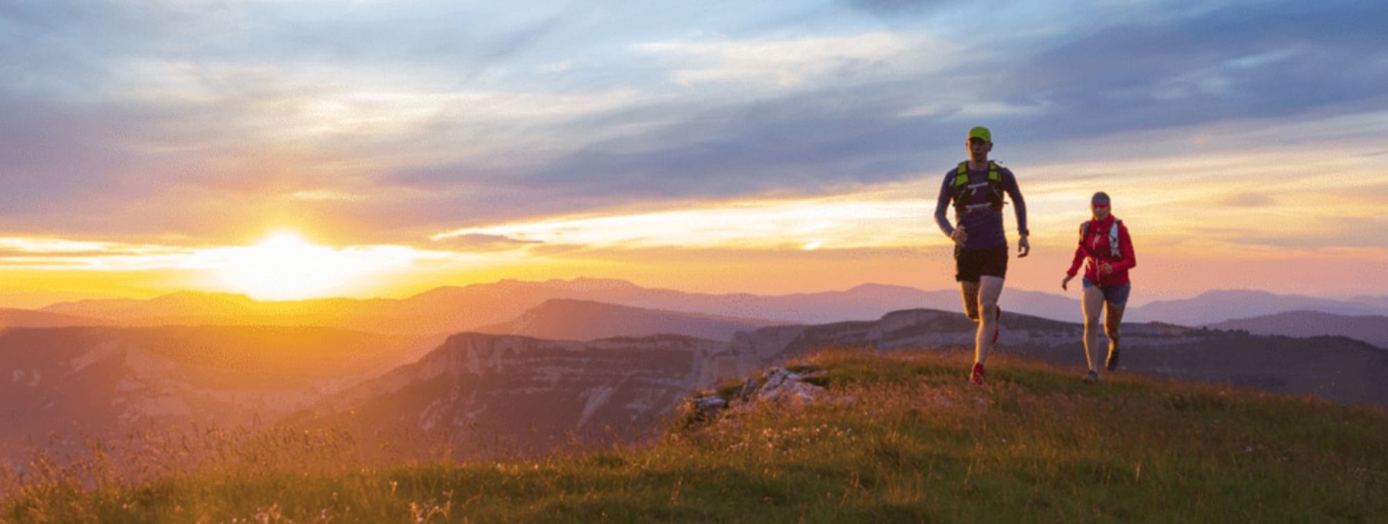 Un coureur court dans la montagne avec le soleil derrière lui