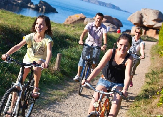 Une famille fait du vélo au bord de la mer