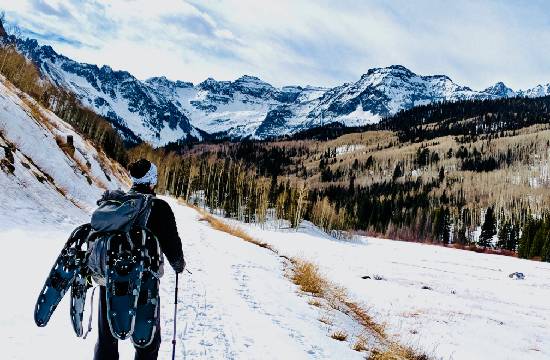 Une homme faisant des raquettes dans les montagnes.