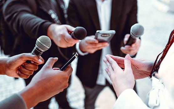 Des journalistes tendent les micros à la présentatrice