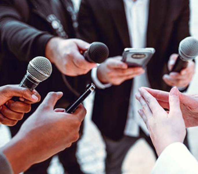 Des journalistes tendent les micros à la présentatrice
