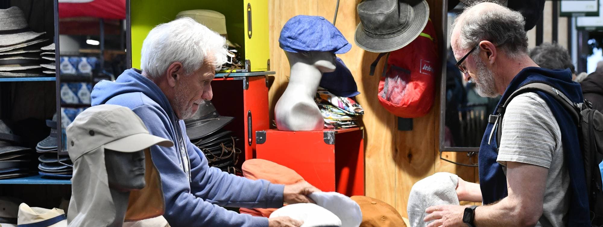 un vendeur montrer des couvres-chef à un homme