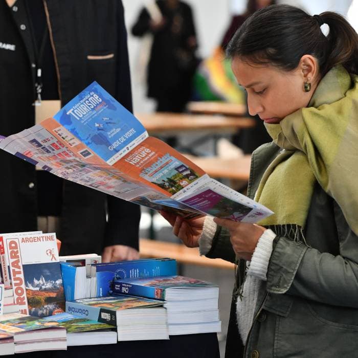 une femme lit le guide de visite du salon