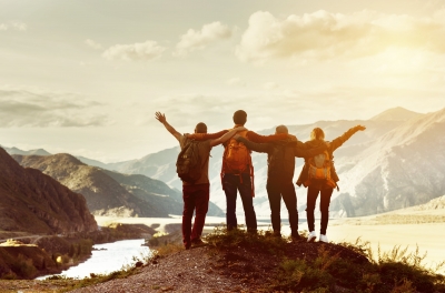 Un groupe de quatre jeunes s'emerveillant devanrt une vue à couper le souffle en montagne. 