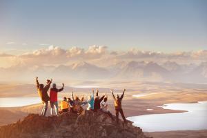 Un groupe d'adultes levant les bras face à la montagne. 