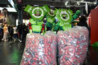 Deux personnes déguisées en poubelles recyclables ayant dans les mains des sacs remplis de canettes recyclées